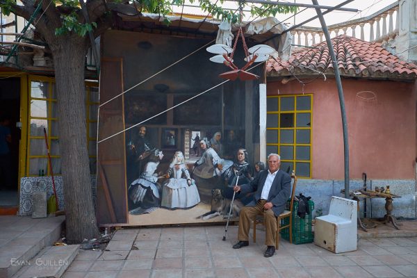 Fotografía de calle. El pintor Miguel Ángel Valverde sentado junto a una réplica de Las Meninas.